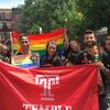 Students and alumni carrying a rainbow Pride flag and a Temple Flag.