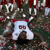 A Temple football player laying on the confetti covered field.