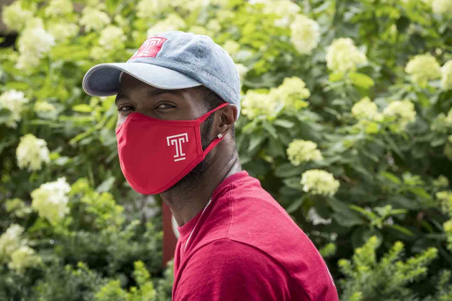 A Temple community member wearing a Temple-branded mask.