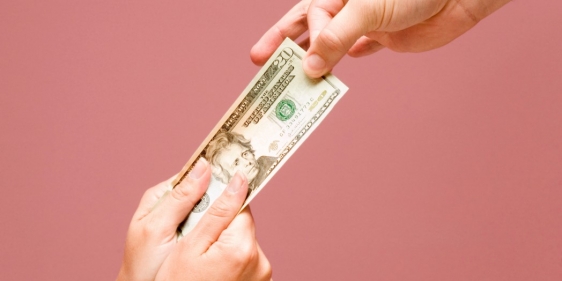 Hands pulling a twenty dollar bill from opposite end